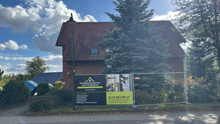 Bauzaunbanner für Hausmeisterservice und Trockenbau Ingo Duderstadt vor einem Wohngebäude.